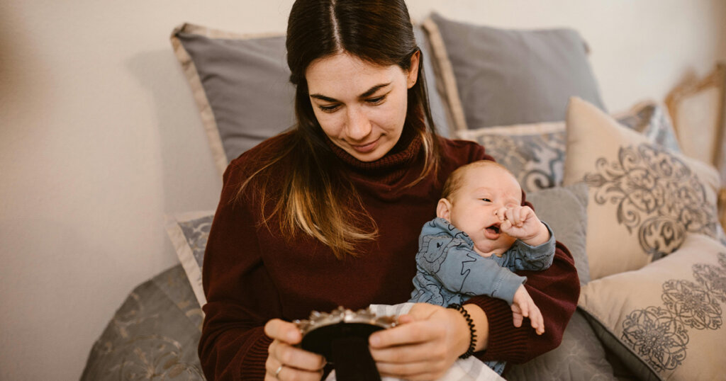 Mother Holding Her Baby while Looking at a Picture Frame