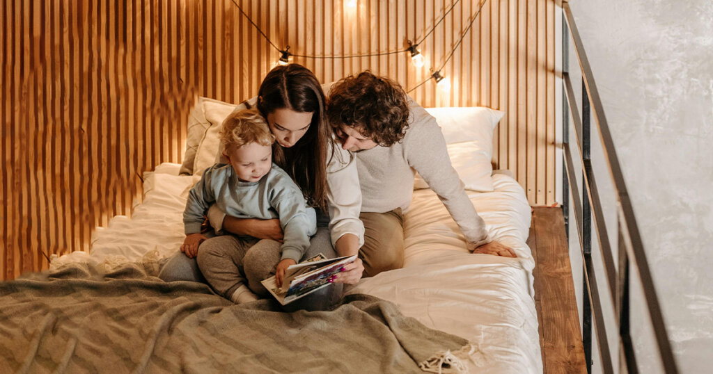 baby and parents reading book on bed