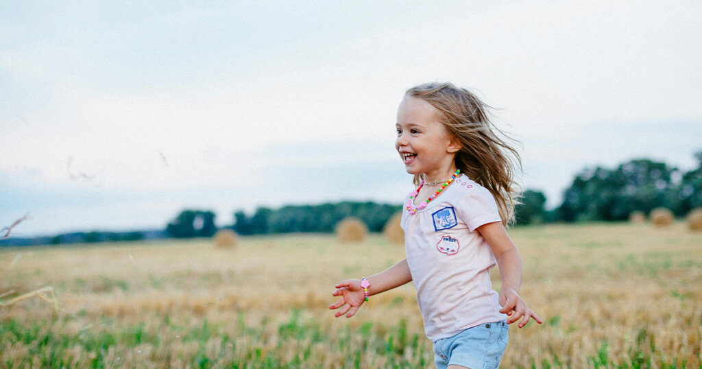 little girl running in the green feilds