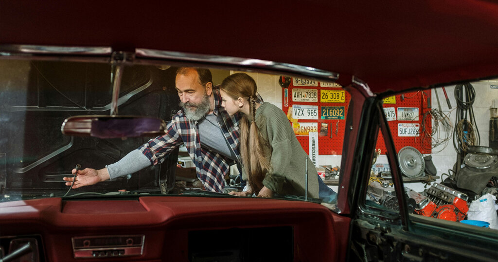 A Mechanic Teaching his Daughter How to Fix a Car
