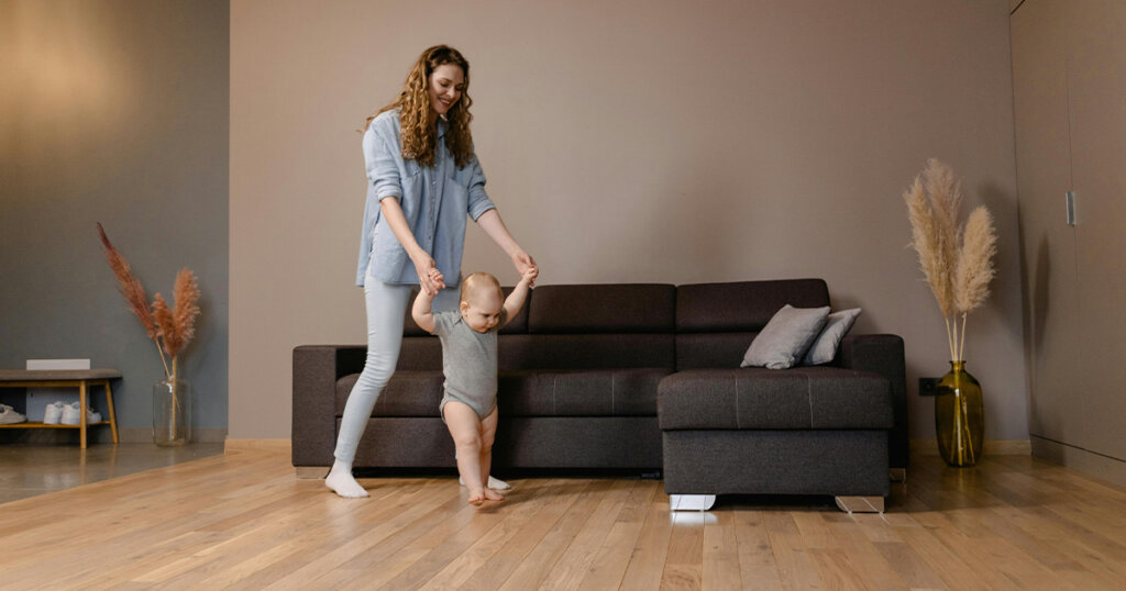 Woman in Blue Denim Jacket and Gray Pants Standing Beside Black Couch