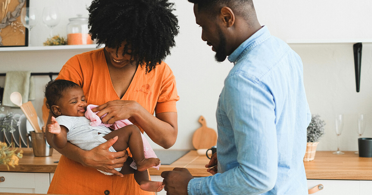Black Mom clearing newborn's mouth while dad watching