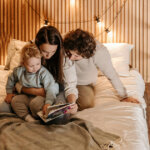 baby and parents reading book on bed
