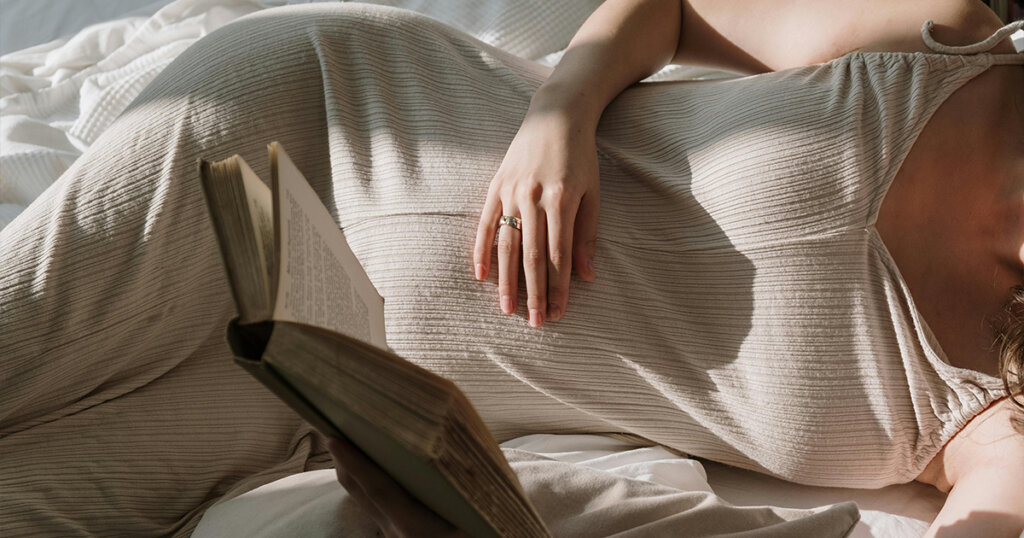 A Pregnant Woman Reading a Book while Lying Down