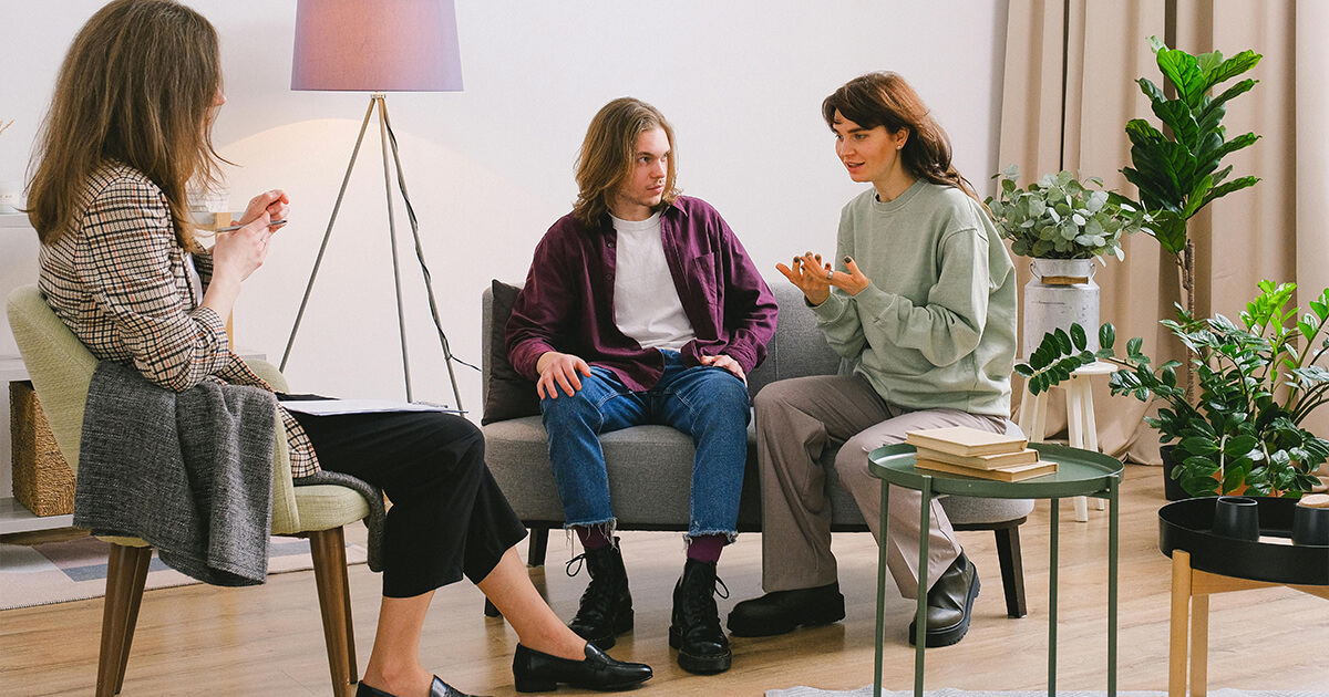 Couple talking with psychologist in light room