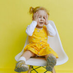 Girl In Yellow Dress Covering Her Face With Her Hands