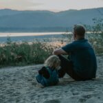 Father Sitting on Sand with a Child