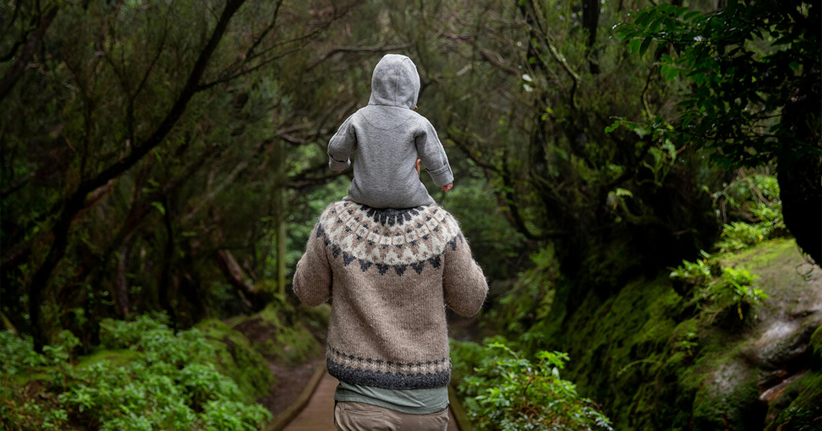 Anonymous man with baby on shoulders walking away