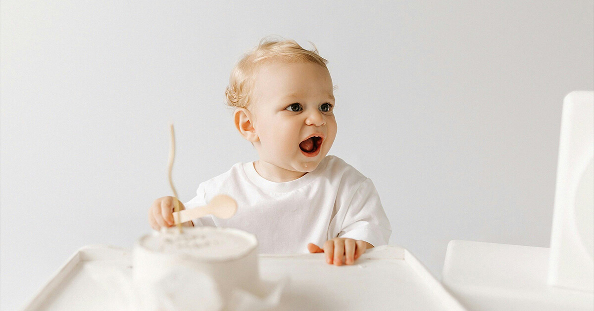 Blonde Baby Boy Sitting with Birthday Cake