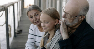 Girl in Gray Long Sleeve Shirt Sitting beside Man in Black Jacket and Woman in White and Black Stripe Jacket