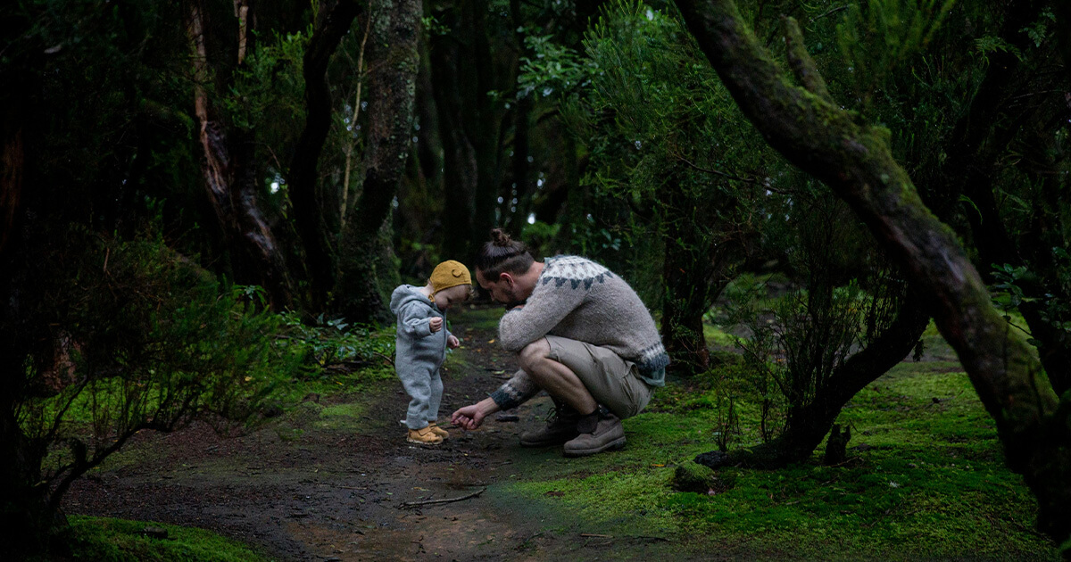 Father playing with son in fir forest