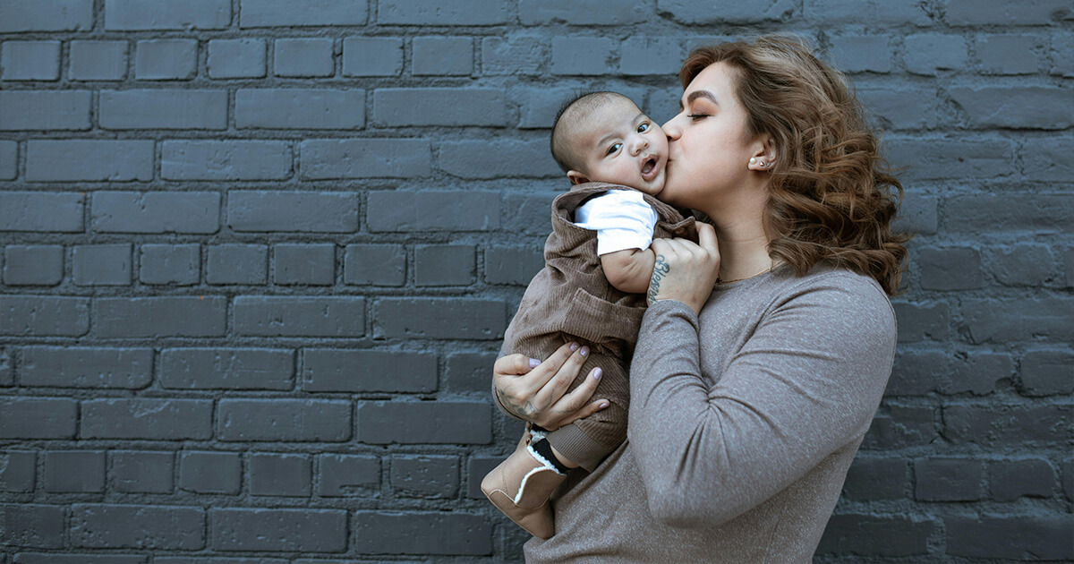 Woman in Brown Long Sleeve Shirt Kissing a Baby