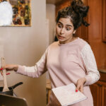 woman cooking and watching laptop