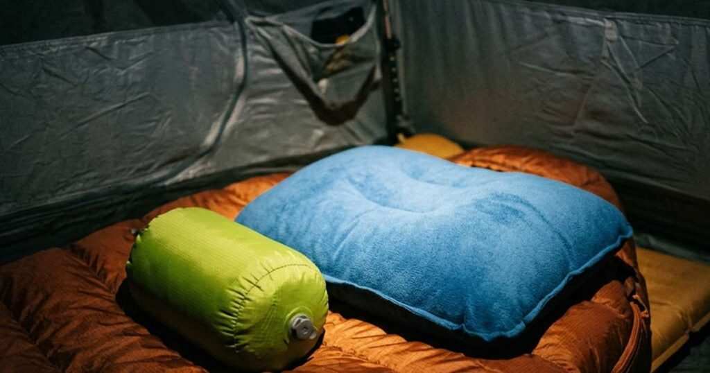 Compact inflatable pillow next to a larger foam fill pillow inside a tent